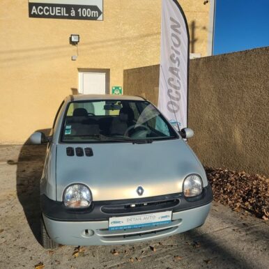 Renault Twingo grise d'occasion chez Detail Auto à Pamiers, avec drapeau Occasion et panneau Accueil à 100m.