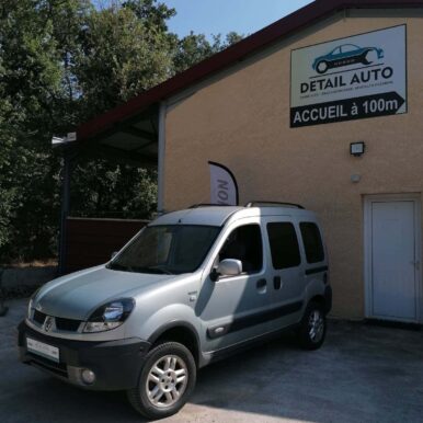 Renault Kangoo grise devant l'enseigne Detail Auto, expert en pièces détachées et véhicules d'occasion.
