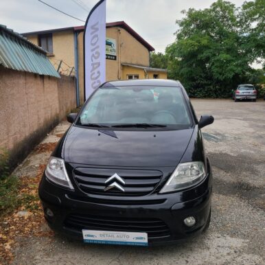 Citroën noire d'occasion chez Detail Auto à Pamiers avec enseigne et drapeau publicitaire.