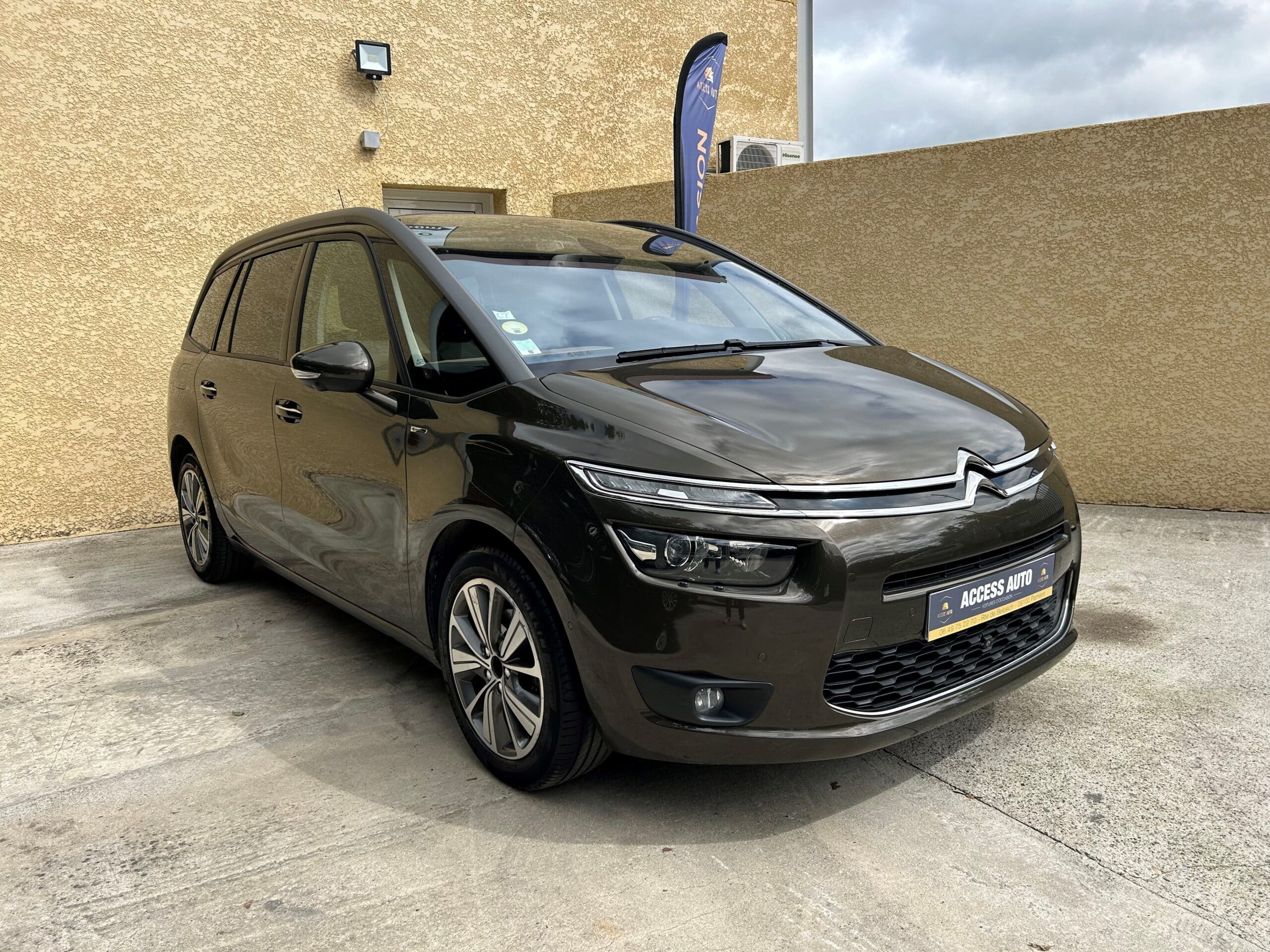 Citroën C4 Grand Picasso marron d'occasion exposée chez Access Auto devant un bâtiment moderne texturé.