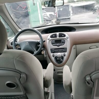 Intérieur d'une Citroën Xsara Picasso avec sièges en tissu gris et tableau de bord central numérique.
