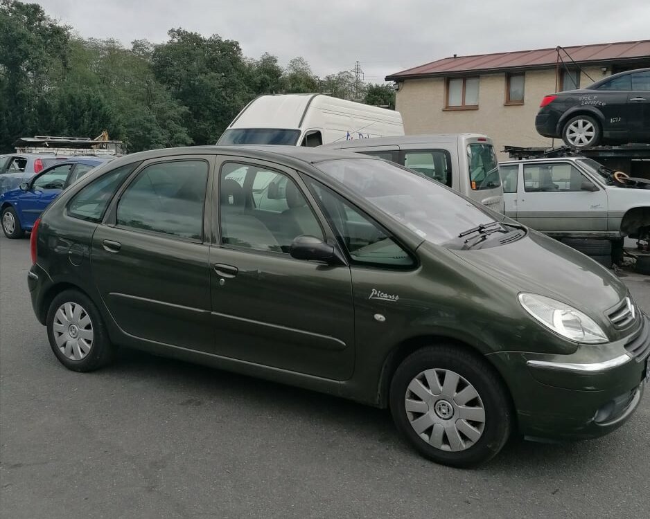 Citroën Xsara Picasso vert foncé avec inscription Picasso sur la porte, garée sur un parking.