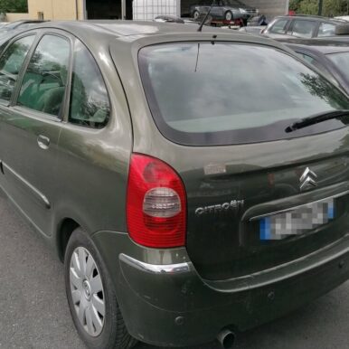 Citroën Xsara Picasso vert foncé, vue arrière sur un parking, logo Citroën et badges visibles.