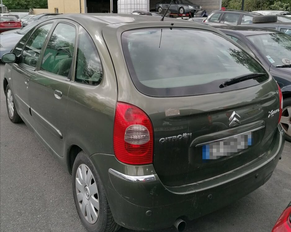 Citroën Xsara Picasso vert foncé, vue arrière sur un parking, logo Citroën et badges visibles.
