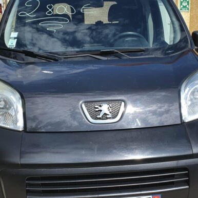 Peugeot Bipper d'occasion gris foncé, prix 2800€ sur le pare-brise, vue de face avec logo lion.