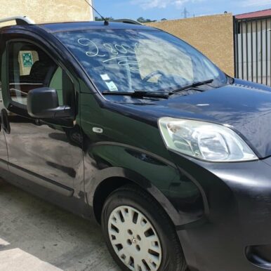 Peugeot Bipper noir d'occasion à vendre 2800€ avec barres de toit sur un parking extérieur ensoleillé.
